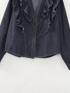 Close-up of a dark blue denim jacket with ruffled neckline and button-down details