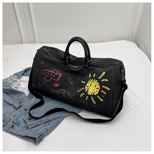 Detail of black cylinder canvas duffel bag featuring vibrant graffiti and travel patterns
