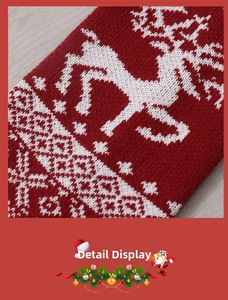 Detail of red knitted Christmas stocking featuring white reindeer and snowflake patterns