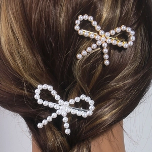 Elegant bow hair clips with pearls and tassels shown on a braided hairstyle