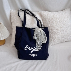 Detail of navy canvas tote with Bonjour magic print and lace bow on striped handle