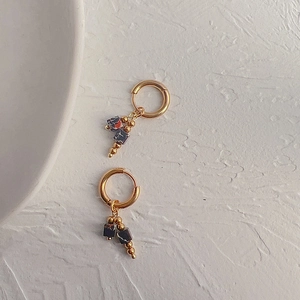 Detailed close-up of retro 18k gold earrings with deep blue square stone pendants