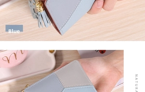 Détail du portefeuille en cuir bleu avec pompon et pendentif chat sur une table
