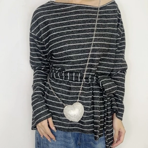 Silver heart-shaped crossbody bag with rhinestones and metal chain strap shown on model