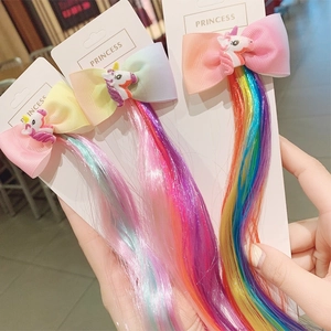 Detailed view of three rainbow unicorn hair clips with long colorful synthetic hair extensions
