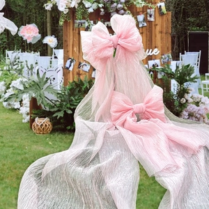 Pink pleated fabric bow for wedding backdrop or party decoration in outdoor garden setting