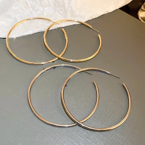 Minimalist oversized gold and silver hoop earrings in polished metal finish