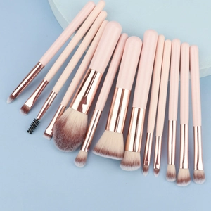 Dettaglio di 13 pennelli trucco professionali con manici rosa crema e morbide setole bicolore