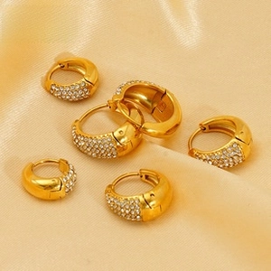 Macro shot of gold-plated hoop earrings with pave-set cubic zirconia on silk cloth