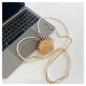 Detailed macro view of a golden shell-shaped evening bag with pearl and chain straps