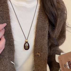 Detail von Tigerauge Steinanhänger mit Goldperle an brauner Kordel am Model
