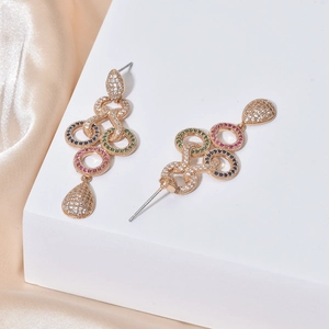 Macro side view of long tassel gold earrings with colorful zircon on champagne silk