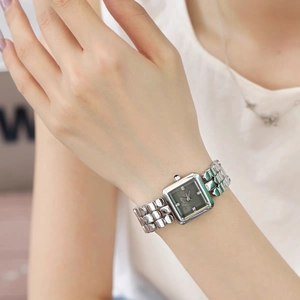 Detail of square quartz watch with silver mesh band and diamond markers on model wrist