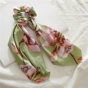 Detail of green satin scrunchie with pink floral pattern and long elegant ribbon