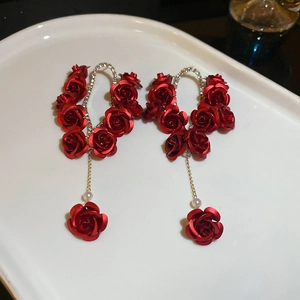 Macro detail of red rose flower tassel earrings with pearls and gold finish
