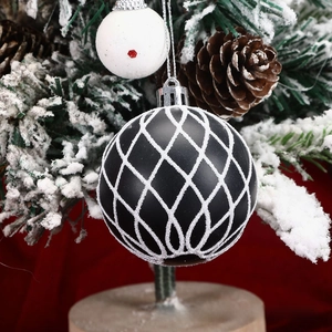Detail of matte black Christmas ball with white glitter mesh on snowy pine branch