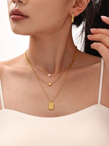 Detail of layered gold stainless steel necklace with star pendants and shell pearl