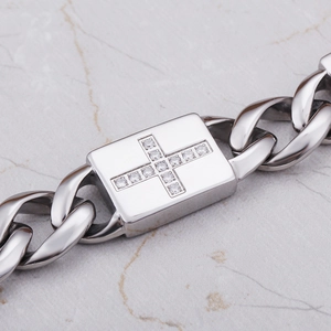 Détail macro du bracelet à maillons cubains avec croix sertie de diamants brillants