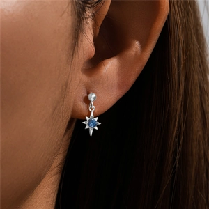 Macro shot of S925 sterling silver star stud earring with a blue gemstone on ear