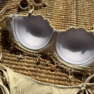 Detail of shell-shaped bikini top with star charms and ribbed texture on woven mat