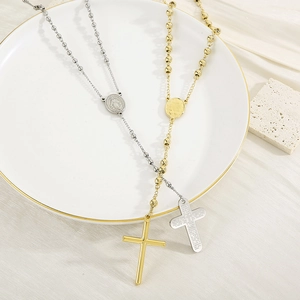 Flat lay of gold and silver rosary cross necklaces on white decorative plate