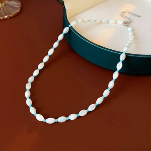 Detailed view of sea blue bead necklace with white oval pearls in a green jewelry box