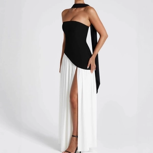 Detail of elegant black tube top dress with white flowing slit skirt and neck strap