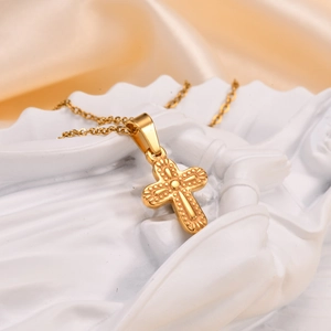 Macro detail of golden cross pendant with vintage relief on sculptural white base