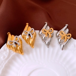 Close-up of metallic bow earrings with irregular wave texture in gold and silver finish