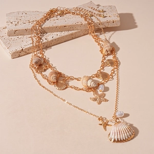 Detail of layered gold seaside necklace with natural shells, starfish and pearl charms