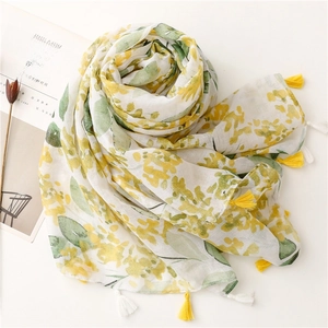 Detail of yellow floral print scarf with soft fringe tassels on white cotton fabric
