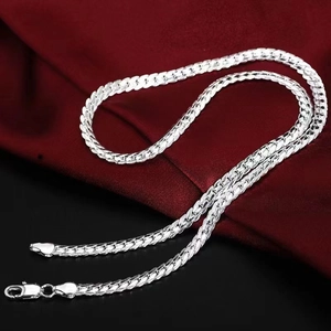 Detailed view of silver flat curb chain necklace on elegant dark red fabric background
