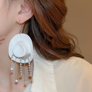 Macro shot of white cowboy hat earring with sparkling rhinestone fringe and silver chains