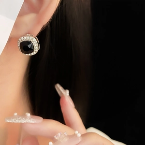 Gros plan d'un mannequin portant des boucles d'oreilles carrées noires avec halo de diamants