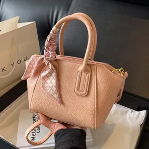 Pink lychee grain leather bucket bag with decorative ribbon and gold hardware accents