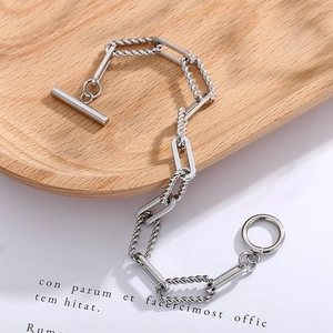 Detailed view of silver stainless steel chain bracelet with OT toggle clasp on wooden tray