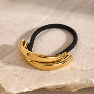 Close-up of golden polished double arc hair tie on premium marble background