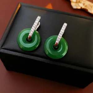 Élégantes boucles d'oreilles chinoises en jade et diamants sur une boîte à bijoux