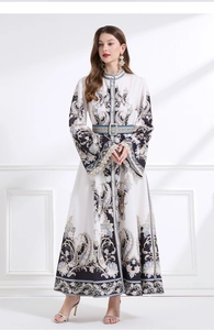 Détail du motif paisley sur une robe longue blanche à col montant avec ceinture assortie