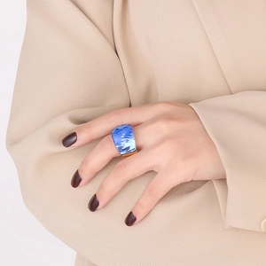 Blue faceted crystal glass ring with gold titanium base on model wearing beige blazer