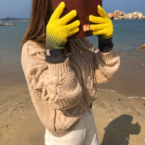 Detail of gradient rainbow knit gloves with touch screen tips in a beach setting