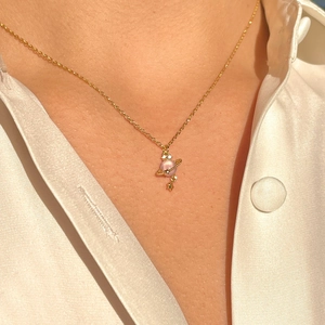 Chic gold Saturn planet necklace with pink gemstone and crystals on a silk shirt model