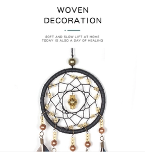 Detailed view of black woven dreamcatcher with golden beads and hanging feathers
