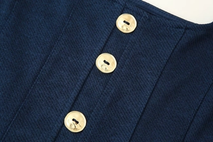 Détail macro de boutons métalliques dorés sur la texture d'un tissu sergé bleu marine