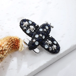 Detailed view of airplane brooch with blue rhinestones and pearls on white stone