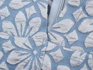 Detailansicht des blauen Jacquard-Stoffes mit silbernem Blumenmuster und Metallreißverschluss