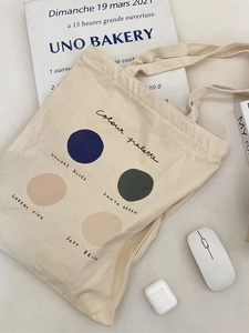 Minimalist cream canvas tote bag with a colorful palette print and shoulder straps
