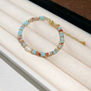 Detail of beaded bracelet with blue and red-brown beads and a natural freshwater pearl