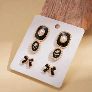 Detail view of retro pearl rose earrings and black bow studs on a display card