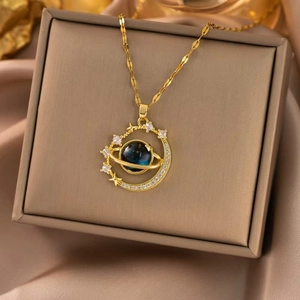 Detail shot of golden planet necklace with blue orb and crescent moon frame on silk box